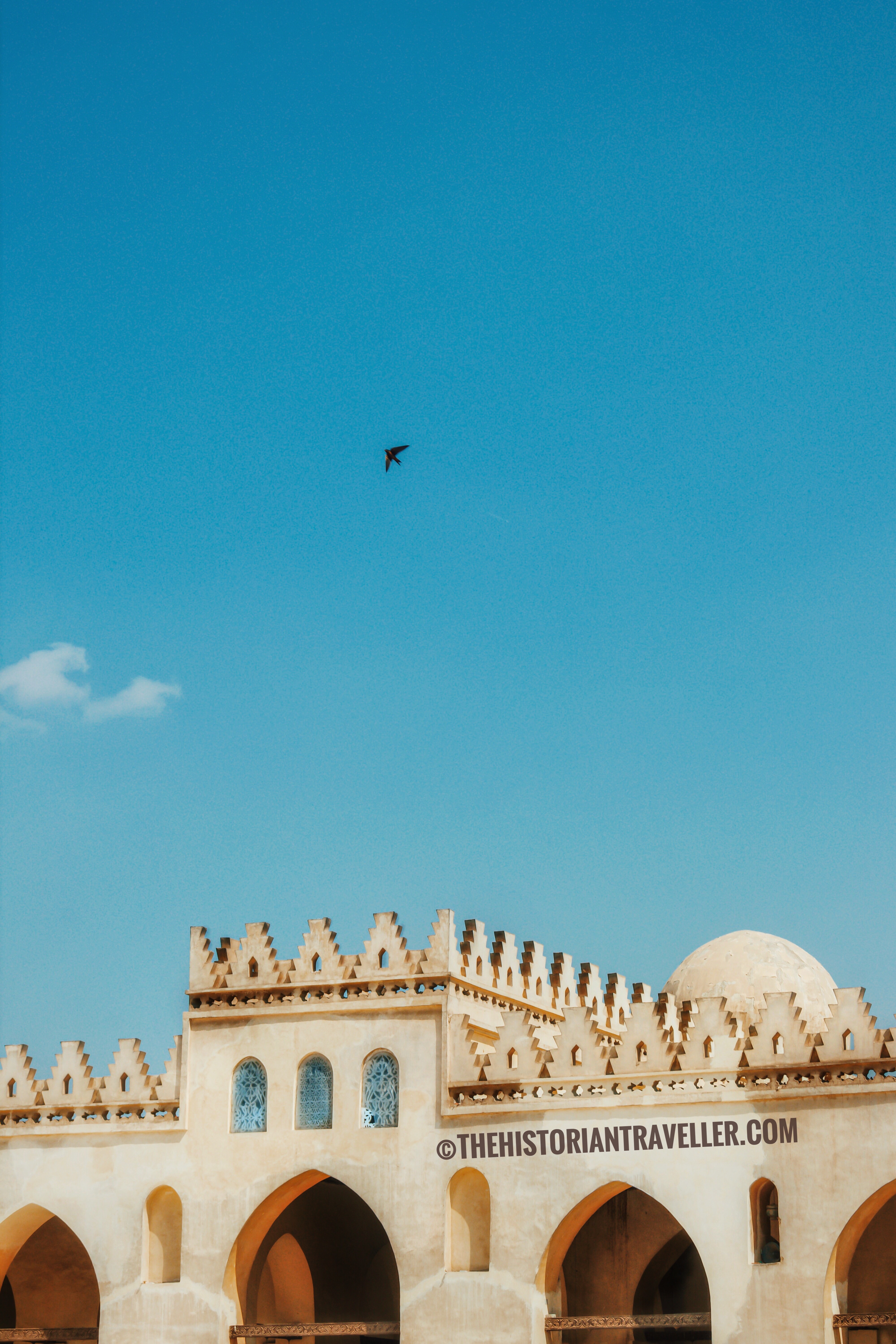 islamic cairo walking tour - minimalistic view of the al-hakim mosque main facade with a bird flying